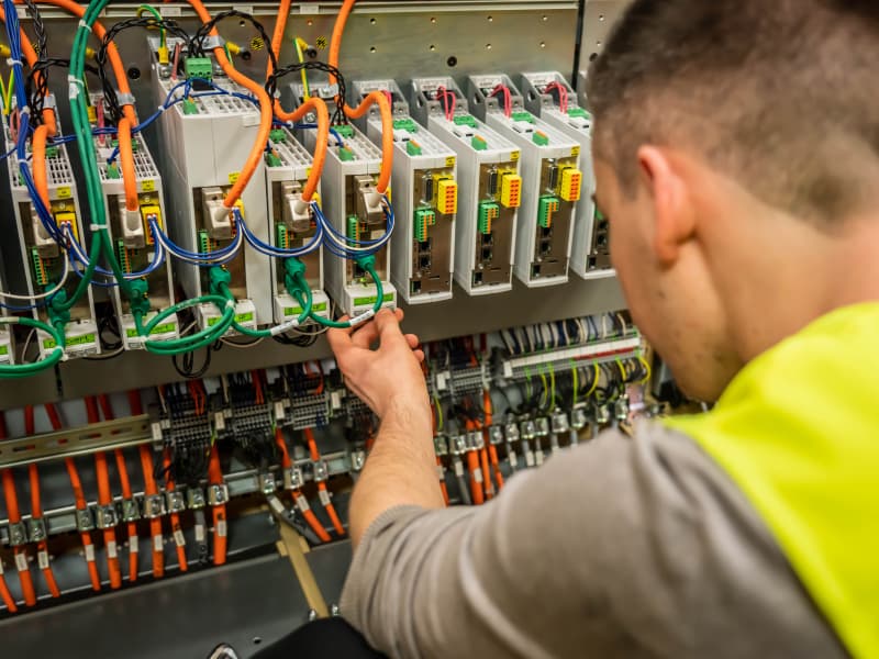 Ein Techniker ist damit beschäftigt, ein Panel zu verdrahten und demonstriert dabei seine Fähigkeiten in Elektrotechnik und Problemlösung.